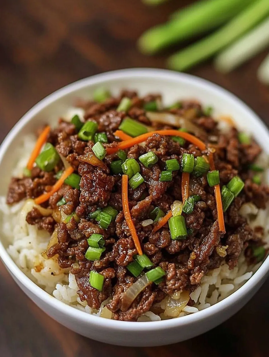 A bowl of beef and rice with green onions.