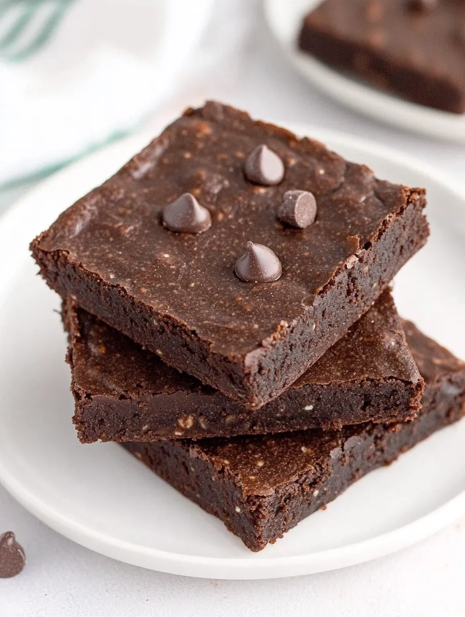 A stack of brownies with chocolate chips on top.