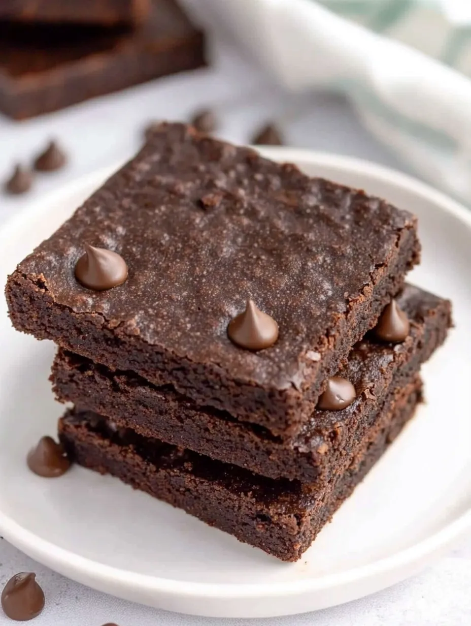 A stack of brownies with chocolate chips on top.