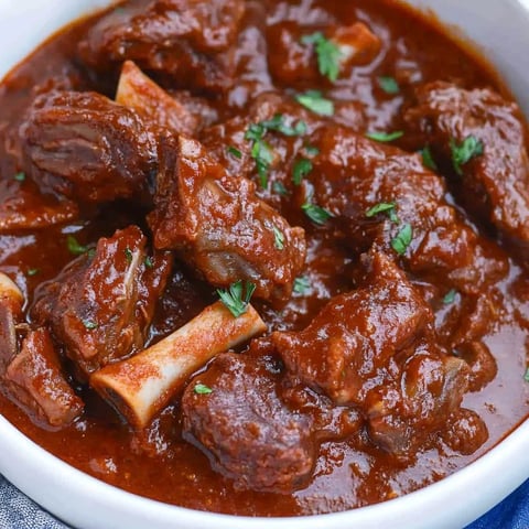A bowl of beef short ribs in a brown sauce.