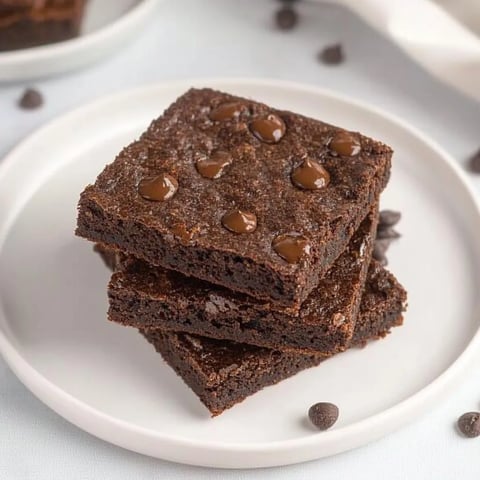 A stack of brownies with chocolate chips on a plate.